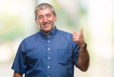 Seyir ve başparmak yanında yukarıyı mutlu yüz ile gülümseyen izole arka plan üzerinde üst düzey yakışıklı.