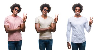 Kolaj bir Afrikalı-Amerikalı genç adam mutlu yüz zafer işareti yaparken kameraya göz kırpıyor ile gülümseyen izole arka plan üzerinde güneş gözlüğü takıyor. İki numaralı.