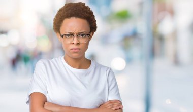 İzole arka plan şüpheci ve çapraz kolları olan yüzündeki gergin, onaylamayan ifade gözlüklü güzel genç Afro-Amerikan kadın. Negatif kişi.