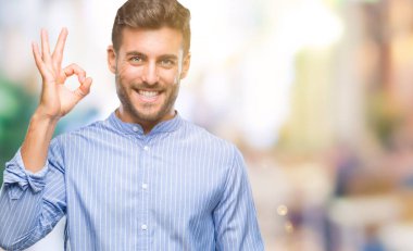 Gülümseyen izole arka plan üzerinde genç yakışıklı adam el ve parmaklar ok işaretiyle yapıyor olumlu. Başarılı ifade.