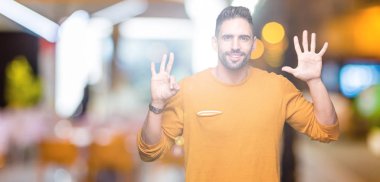 Yakışıklı delikanlı gösterilen ve parmakları ile işaret izole arka plan üzerinde kendinden emin ve mutlu gülümseyerek süre sekiz numara.