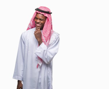 Geleneksel keffiyeh emin çapraz kollar ve çeneme kaldırdı el ile gülümseme ile kameraya bakarak izole arka plan üzerinde giyen genç Arapça Afrika adam. Pozitif düşünce.