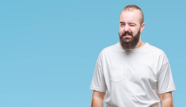 Seksi bir ifadeyle, neşeli ve mutlu yüzünü kameraya bakarak göz kırpıyor izole arka plan üzerinde rahat t-shirt giyen genç beyaz hipster adam.