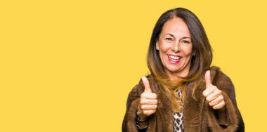 Vizon ceket onaylama giyen güzel orta yaş zarif kadın el ile pozitif jest yapıyor gülümseyen ve başarı için mutlu yaşasın. Kamera, kazanan jest arıyorsunuz.