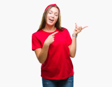 Gülümseyen ve iki elleri ve parmakları ile tarafına işaret kamera bakarak izole arka plan üzerinde beyaz genç güzel kadın.