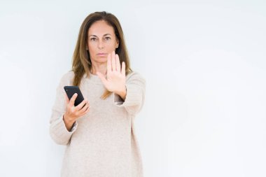 Açık eliyle dur işareti ile ciddi ve kendine güvenen ifade, savunma jest yapıyor izole arka plan üzerinde akıllı telefon kullanan orta yaş kadın