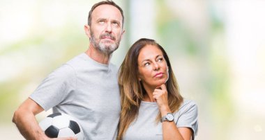 Soru, çok karışık fikir hakkında düşünme futbol futbol topu izole arka plan üzerinde ciddi tutan orta yaş İspanyol çift yüz