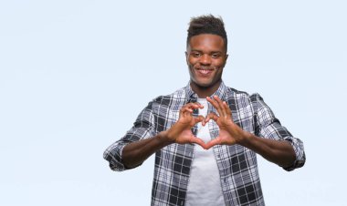 Afrikalı-Amerikalı genç aşık kalp simgesi ve elleriyle şekil gösteren gülümseyen izole arka plan üzerinde. Romantik kavramı.