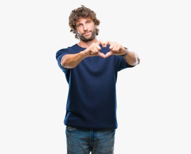 Yakışıklı İspanyol modeli aşık kalp simgesi ve elleriyle şekil gösteren gülümseyen izole arka plan üzerinde kış kazak giyen adam. Romantik kavramı.