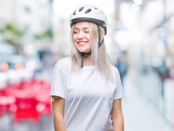 年轻的金发女子戴着骑自行车的安全头盔在孤立的背景看身边与微笑的脸上 自然的表达 笑的自信 — 图库照片
