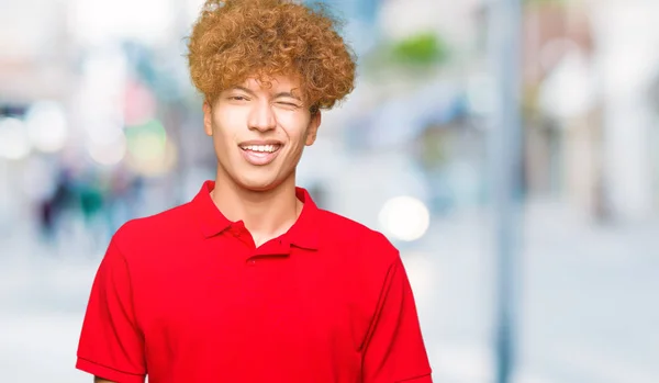 Joven Hombre Guapo Con Pelo Afro Vistiendo Camiseta Roja Guiñando — Foto de Stock