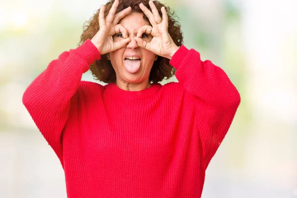 舌を出して指を通して見る目をこだわりの双眼鏡のような ジェスチャーを行う分離の背景に美しい中間エイガー シニア女性赤冬セーター クレイジー式 — ストック写真