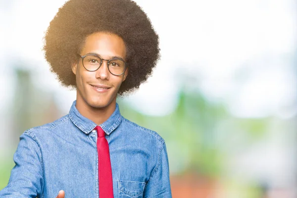 Gözlük ve kırmızı giyen afro saçlı genç Afro-Amerikalı iş adamı tebrik ve davet edici olarak gülümseyen dostu sunan karşılıklı bağla. Başarılı iş.
