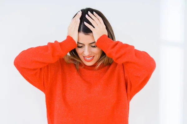 年轻女子穿着休闲红色毛衣在孤立的背景下遭受头痛绝望和压力 因为疼痛和偏头痛 双手放在头上 — 图库照片