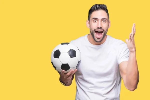 サッカー サッカー ボールの上に保持している若い男隔離背景非常に幸せと興奮 勝者式笑顔で叫んで勝利を祝ってと手を上げた — ストック写真