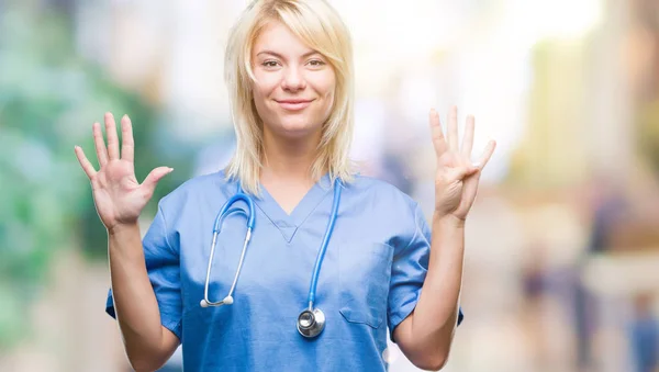 年轻美丽的金发碧眼的医生妇女穿着医疗制服在孤立的背景显示和手指 同时微笑着自信和快乐 — 图库照片