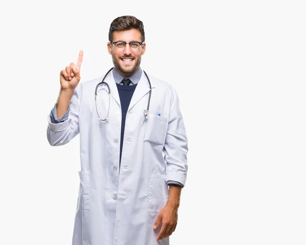 年轻英俊的医生男子在孤立的背景显示和指向手指第一 而微笑着自信和快乐 — 图库照片
