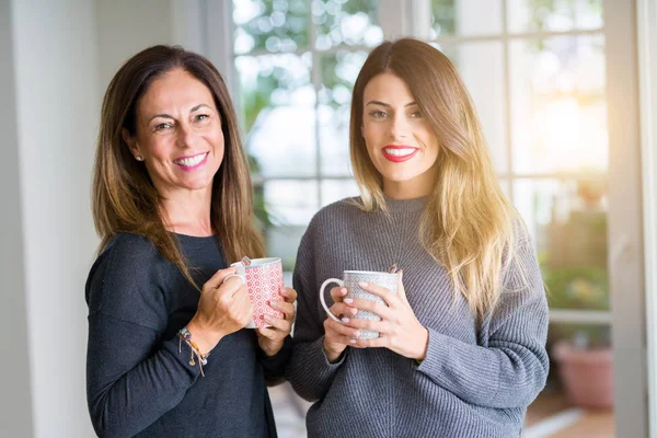 Beautiful family of mother and daughter together drinking a cup of coffee at home