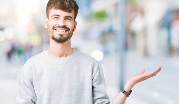 Jonge Knappe Man Dragen Sweatshirt Geïsoleerde Achtergrond Lacht Vrolijk Presenteren — Stockfoto