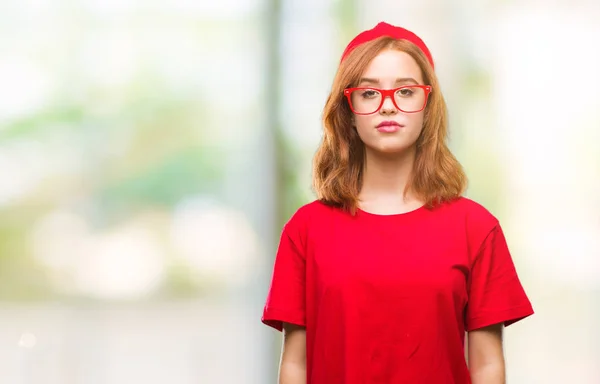 Young beautiful woman over isolated background with serious expression on face. Simple and natural looking at the camera.