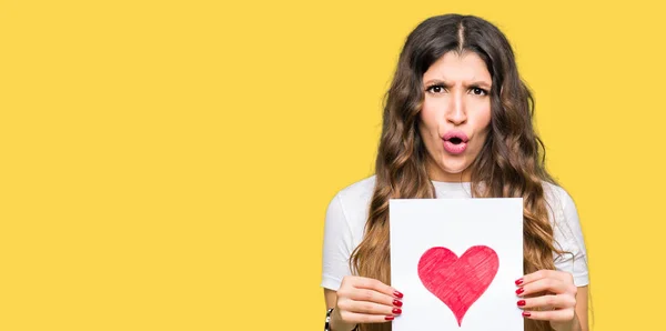 Young Adult Woman Holding Card Red Heart Scared Shock Surprise — Stock Photo, Image