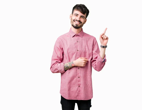 年轻的帅哥穿着粉红色的衬衫在孤立的背景与一个灿烂的笑容在脸上 用手和手指指着一边看着镜头 — 图库照片