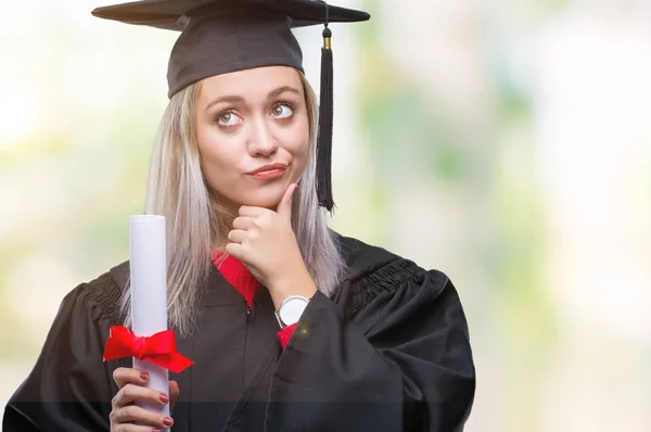 若いブロンドの女性に関する質問は 非常に混乱して考え分離背景深刻な顔を考えての上の学位を保持する大学院の制服を着て — ストック写真