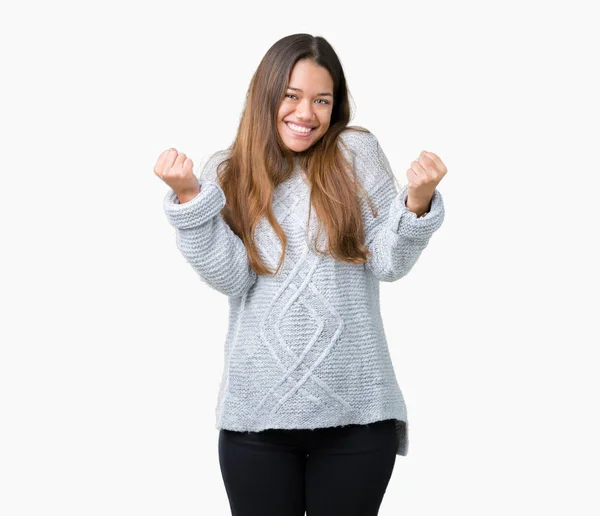 年轻美丽的黑发妇女穿着毛衣在孤立的背景庆祝惊讶和惊讶的成功与手臂抬起和睁大眼睛 优胜者概念 — 图库照片