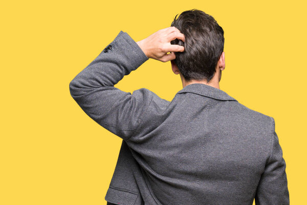 Молодой бизнесмен в очках на изолированном фоне задом наперед думает о сомнениях с поднятой головой
