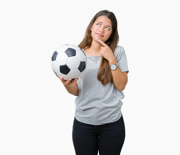 年轻美丽的黑发女子拿着足球在孤立的背景下严重的脸思考问题 很困惑的想法 — 图库照片