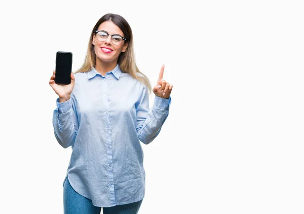 年轻美丽的商业妇女显示空白屏幕上的智能手机在孤立的背景非常愉快的指向与手和手指的一侧 — 图库照片