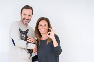 Orta yaş çift holding küçük chihuahua parmak, mükemmel sembolü ile ok işareti yapıyor izole arka plan üzerinde