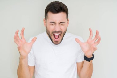 Yakışıklı delikanlı deli ve silah ile başarı için deli kutluyor izole arka plan üzerinde rahat beyaz t-shirt giyen kaldırdı ve heyecanlı çığlık gözler kapalı. Kazanan kavramı