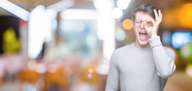 Gülümseyen, parmakları ile mutlu yüz üzerinden seyir göz el ile ok jest yapıyor izole arka plan üzerinde gözlük takan genç yakışıklı adam.