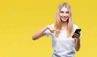 Sürpriz yüz işaret parmağı kendini izole arka plan üzerinde akıllı telefon kullanan genç güzel sarışın kadın