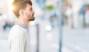 Genç yakışıklı adam giyen kış kazak izole arka tarafına, seyir üzerinde dinlenmek doğal yüz emin gülümseme ile pozuyla profili.