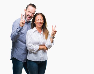 Orta yaş İspanyol iş çift mutlu yüz zafer işareti yaparken kameraya göz kırpıyor ile gülümseyen izole arka plan üzerinde. İki numaralı.