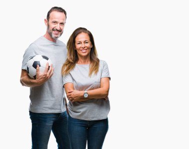 Futbol futbol topu bir gülen surat konumu olan izole arka plan üzerinde tutarak ve diş gösterilen kendine güvenen bir gülümsemeyle gülümseyerek orta yaş İspanyol çift