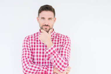 Emin çapraz kollar ve çeneme kaldırdı el ile gülümseme ile kameraya bakarak izole arka plan üzerinde gömlek giymiş yakışıklı delikanlı. Pozitif düşünce.