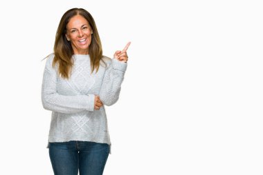 Kameraya bakarak yan el ve parmak ile işaret yüzünde kocaman bir gülümseme ile izole arka plan üzerinde kış kazak giyen güzel orta yaş yetişkin kadın.