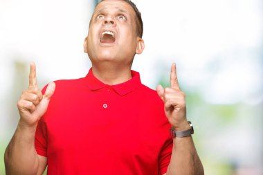 Orta yaş Arap adam izole arka plan üzerinden hayran ve yukarıya bakıp parmakları ile işaret şaşırttı ve silah kaldırdı.