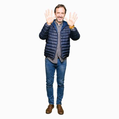 Kış ceket gösterme ve parmakları ile işaret giyen orta yaş yakışıklı adam kendinden emin ve mutlu gülümseyerek süre on numara.