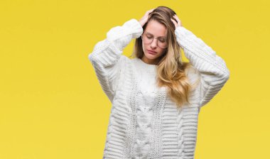 Kış kazak ve güneş gözlüğü çünkü umutsuz ve stresli baş ağrısı acı izole arka plan üzerinde giyen genç güzel sarışın kadın ağrı ve migren. Ellerini kafasına.