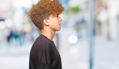 Afro saçlı tarafına, seyir siyah t-shirt giyen genç yakışıklı adam sakin ol kendine güvenen gülümseme ile doğal yüz pozuyla profili.