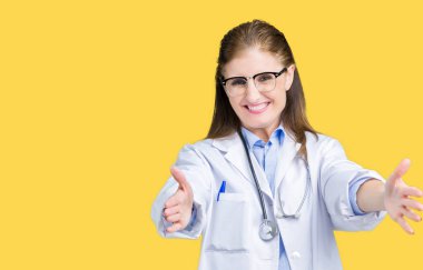 Orta yaş olgun doktor kadın ile gülümseyerek kameraya bakarak izole arka plan üzerinde tıbbi bir palto giyiyor silah sarılmak için açın. Neşeli ifade kucaklayan mutluluk.