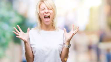 Kızgın ve çığlık kaldırdı ve kapalı gözleri heyecanlı silah ile başarı için deli kutluyor izole arka plan üzerinde beyaz t-shirt giyen genç güzel sarışın kadın. Kazanan kavramı