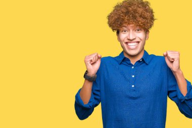 Genç yakışıklı zarif adam afro saç kutlama ile şaşırttı ve başarı için kaldırdı kollarını açarak hayrete ve gözleri açık. Kazanan kavramı.