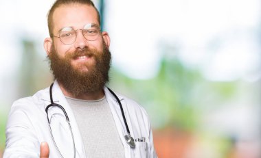 Tıbbi giyen sakallı genç sarışın doktor adam kat gülümseyen dostu sunan karşılıklı olarak tebrik ve misafirperver. Başarılı iş.