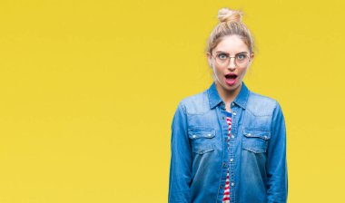 Korkuyor ve şok sürpriz ifade, korku ve heyecan yüz ile izole arka plan üzerinde gözlük takan genç güzel sarışın kadın.