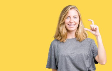 İzole arka plan gülümseyen ve süre seyir ve kamera boyutu işaret parmaklarıyla yapıyor el ile kendinden emin eller üzerinde büyük boy rahat t-shirt giyen güzel ve genç birbayan. Ölçü kavramı.